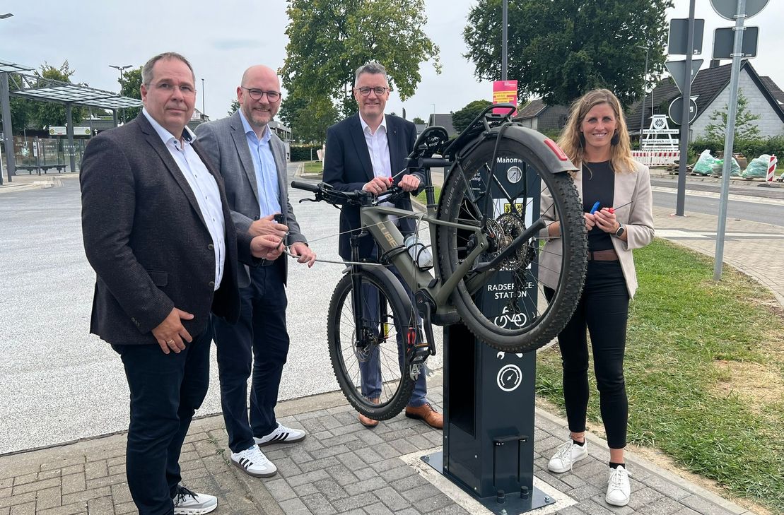 Dirk Leifeld von der Caritas Betriebsstätten GmbH, Roetgens Bürgermeister Jorma Klauss, Städteregionsrat Dr. Tim Grüttemeier und Monschaus Bürgermeisterin Dr. Carmen Krämer prüfen die neue Radservicestation am Imgenbroicher Bushof auf ihre Tauglichkeit.