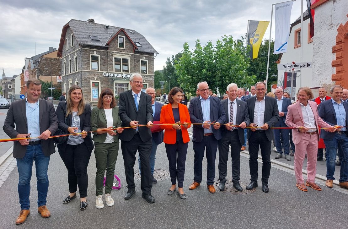 Mit einem großen Bahnhof ist die Freigabe in Anwesenheit von Verkehrsministerin Daniela Schmitt erfolgt. Beim traditionellen Banddurchschneiden reihten sich neben der Ministerin (Mitte roter Blazer) Hans-Michael Bartnick (Leiter LBM Trier; 4. von links), Verbandsbürgermeister Leo Wächter (4. von rechts) und Stadtbürgermeister Wolfgang Port (5.von rechts) ein.