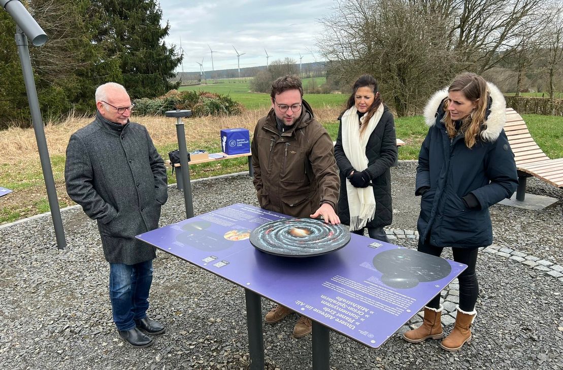 Dominik Hosters vom Naturpark Nordeifel erklärt Monschaus Bürgermeisterin Dr. Carmen Krämer (r.) und Höfens Ortsvorsteher Heinz Mertens das 3D-Modell der Milchstraße am neuen SternenBlick »Nachtschwärmer« auf Alzen. Im Hintergrund Platzgestalterin Ute Frauenkron.