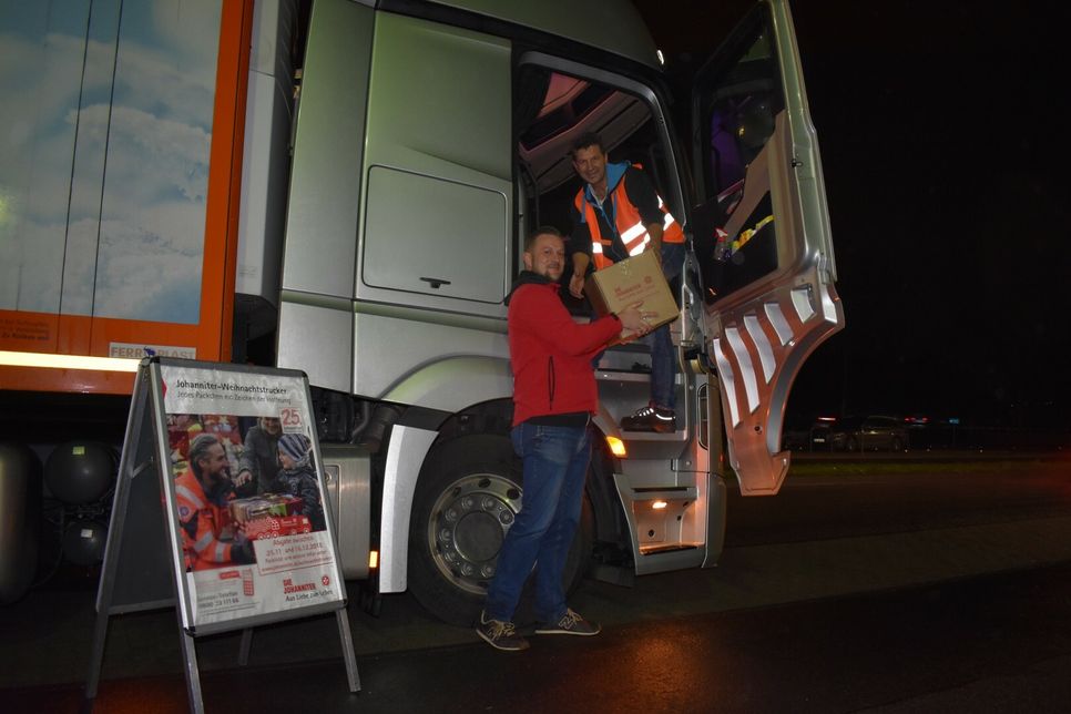 Johanniter-Regionalvorstand Daniel Bialas übergibt eines der WochenSpiegel-Pakete an den Trucker-Fahrer, der den Lkw auch tatsächlich selbst ehrenamtlich nach Rumänien fährt. Das Paket bekommt einen Ehrenplatz auf dem Beifahrersitz.