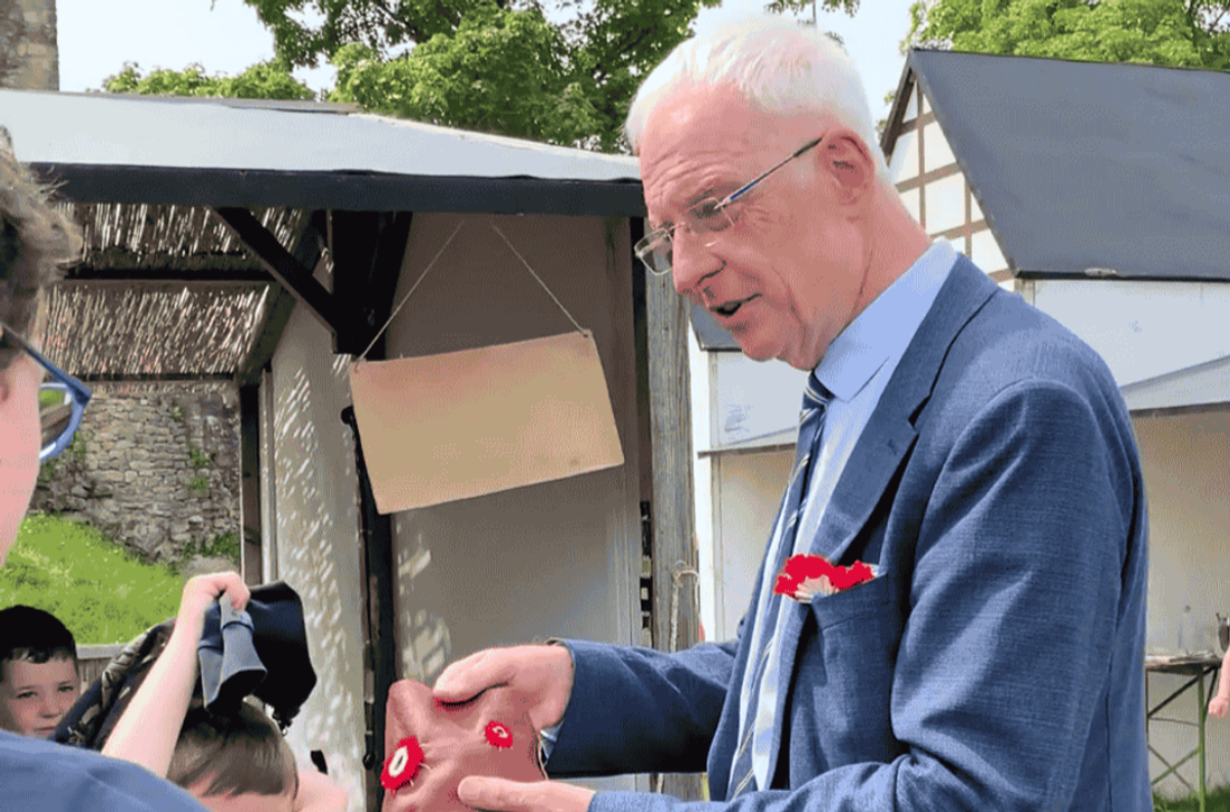 Ein Kind präsentiert OB Wolfram Leibe stolz seinen selbstgenähten Geldbeutel.