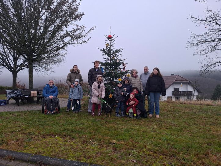 Kinder und Eltern dekorieren den Baum am „Hellejehäusje-Platz“ mit selbst gebastelten Weihnachtskunstwerken.