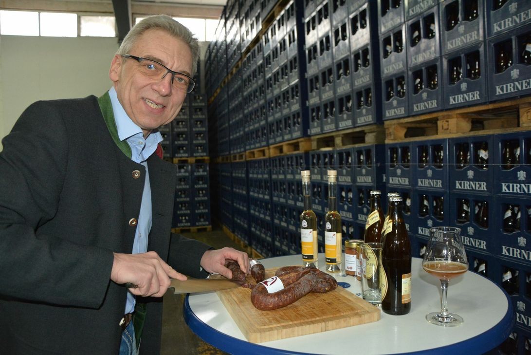 Kaus Nieding (Wildkammer) schneidet seine Wildwurst auf.