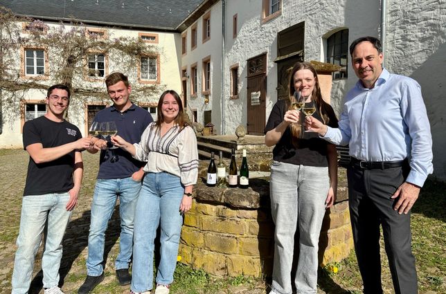 (v.l.): Die jungen Winzer Christof Schuster, Fabian Schafhausen, Vanessa Reuter, Lena Hein und Bürgermeister Guido Wacht laden Sie ins Freilichtmuseum Roscheider Hof zum „WeinGenuss 2026“ ein.