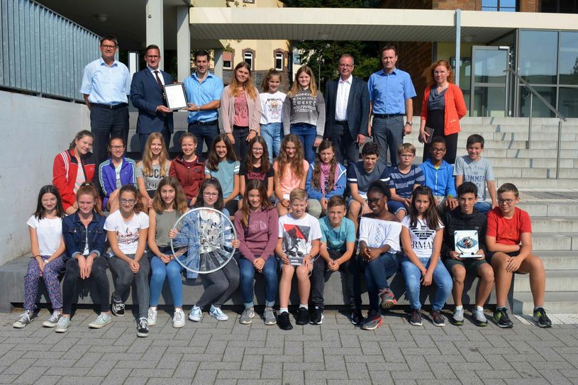 Die Schülerinnen und Schüler der Klasse 7e des Gymnasiums Saarburg haben beim 3malE-Schulwettbewerb von innogy den ersten Preis in der Kategorie »Klasse 5-7« erhalten. Hintere Reihe, von links: Landrat Günther Schartz, Michael Arens (innogy), Fachlehrer Stefan Weirich, der Bürgermeister der Stadt Saarburg Jürgen Dixius, Schulleiter Reimund Leibold sowie Klassenlehrerin Elke Nonn bei der Übergabe des Preisgeldes und der Siegerurkunde. Foto: innogy