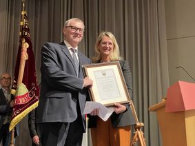 Ortsbügermeisterin Corinna Berendt überreicht Dr. Alexander Saftig die Ernennungsurkunde – begleitet von langanhaltendem Applaus.