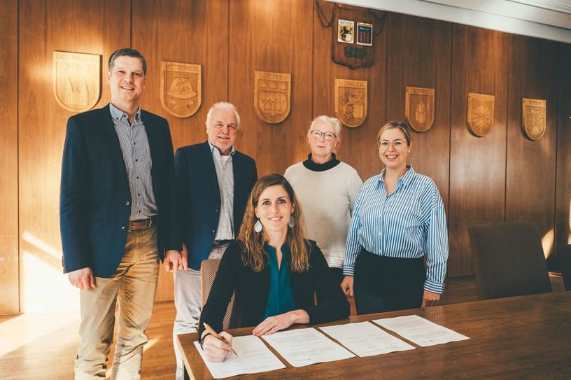 Bürgermeisterin Dr. Carmen Krämer unterzeichnet die Entwicklungsvereinbarung im Beisein von NRW.URBAN-Geschäftsführer Henk Brockmeyer und Projektleiter Klaus-Dieter Büttner, Monika Liedtke, Bauverwaltung der Stadt Monschau sowie Tanja Fischer, Projektteam seitens NRW.URBAN (v.l.).