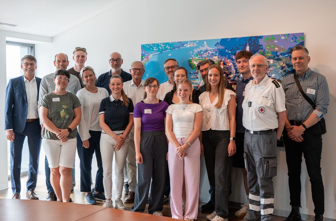 Von links: Klaus Adams (KSK Rhein-Hunsrück), Volker Boch (Landrat), Dr. Stefanie Bender (Amtsärztin, Leiterin GA Simmern), Carl Gummersbach (Praktikant), Dr. Stephanie Zang (Oberärztin Diakonie Kliniken Hunsrück), Guido Scherer (GA), Dr. Louise Brenner, Dr. Georg Brenner, Lisa Etges (Praktikantin), Dr. Lukas Sabel, Cosima Naffin (Praktikantin), Emma Ihmig (Praktikantin), Axel Strähnz, Laura Gregori (Praktikantin), Edon Rufati (Praktikant), Heinz-Dieter Wieß (Kreisbereitschaftsleiter DRK), Dominic Daub (Dezernent).