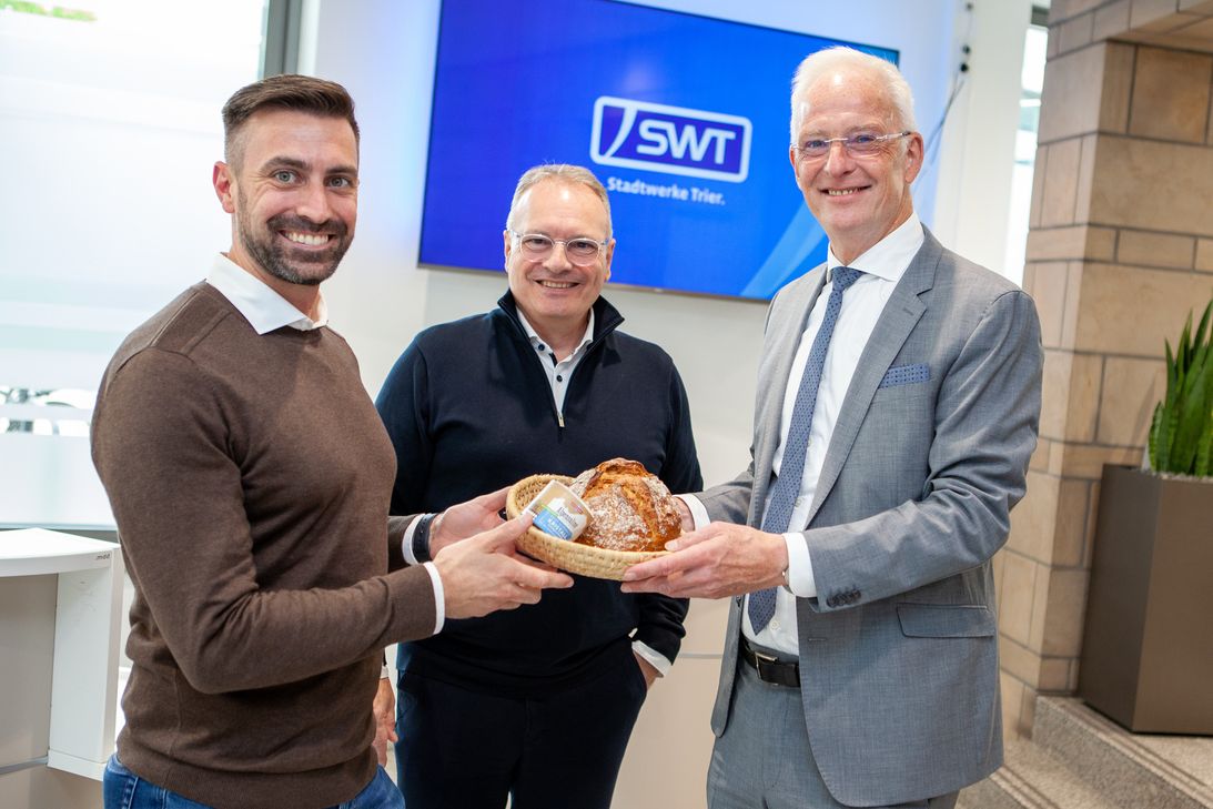 Auf gute Nachbarschaft: OB Wolfram Leibe heißt SWT-Vorstand Arndt Müller und SWT-Vertriebsleiter Marc Bonertz mit Brot und Salz am neuen Standort willkommen (v.r.n.l.).