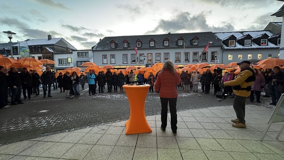 Mit orangen Schirmen als sichtbares Zeichen gehen die Teilnehmenden zum Forum.
