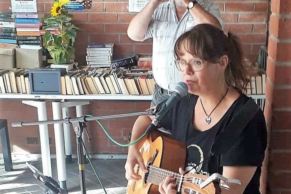 Sylvia Nels begeisterte mit Gesang und Gitarrenspiel zum fünfjährigen Jubiläum der Bücherecke »Im Treff«. Im Hintergrund Christoph Rother, Initiator der Bücherecke.