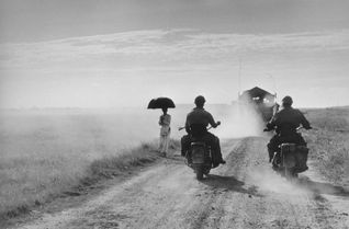 Capa Motorcyclists and woman walking on the road from Nam Dinh to Thai Binh Indochina (Vietnam) May 1954 (c) Robert Capa (c) International Center of Photography Magnum Photos