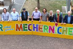 Viel Lust auf ein großes, fröhliches Stadtfest macht das knallbunte, vom Mechernicher Kurator Franz Kruse (5. v.re.) entworfene Kunstwerk, das die Musiker und Verantwortlichen nun vor dem Rathaus präsentierten.