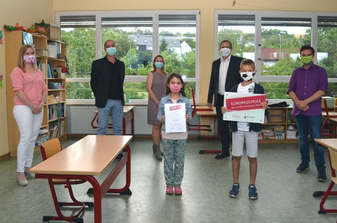 Stolz präsentieren die Schülersprecher Leila Ghanayem und Vincent Lauer die Urkunde und das Schild, die die Grundschule Göttschied nunmehr als Europaschule ausweisen. Helena Dalheimer, Mitglied des Schulelternbeirats, Jugendamtsleiter Michael Schweizer, Schulleiterin Nicole Bier, Oberbürgermeister Frank Frühauf und Frank Schnadthorst vom Bildungsministerium freuen sich über die Auszeichnung.