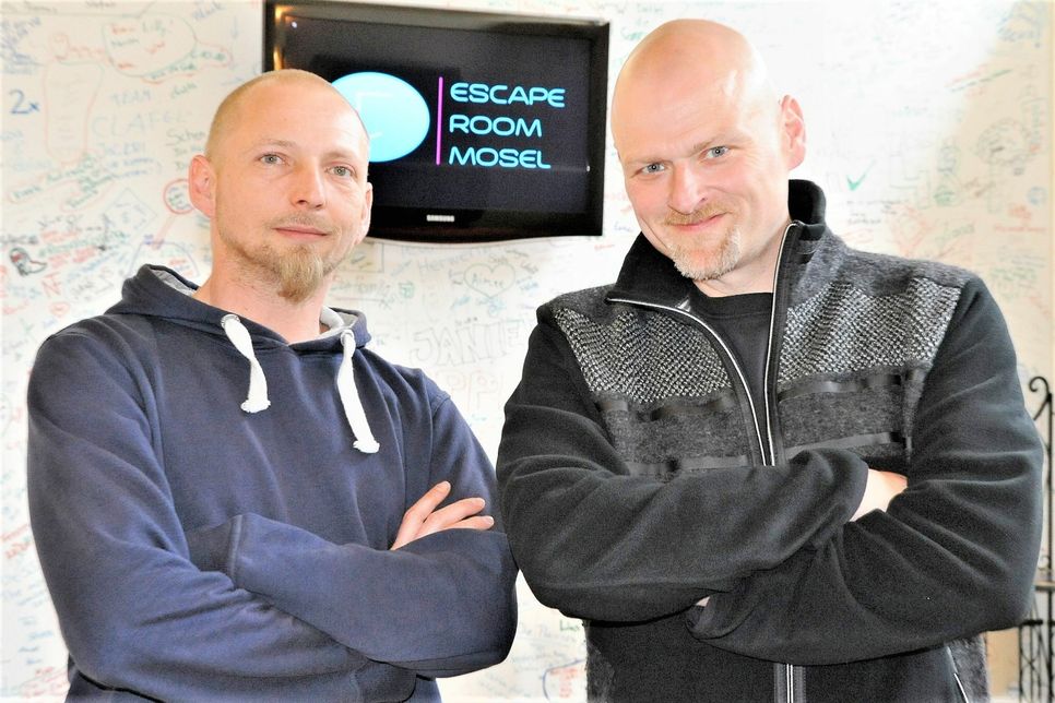 Alexander Wagner (rechts) und Andre Hild-Dreiocker, die Gamemaster des Escape-Rooms-Mosel, vor Wänden mit Graffiti-Eindrücken ihrer Gäste.                      Foto: Ursula Schmieder