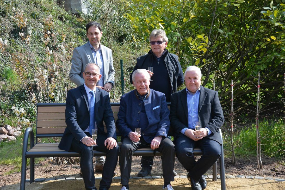 Bürgermeister Joachim Weber (v.l.n.r), Ehrenbürger Franz Görtz und Karl-Peter Jochem, stellv. Vorsitzender des Bürgervereins Berendsborn, sitzen gemeinsam auf einer der neuen Bänke, die der Verein in der vergangenen Woche am Bach nahe des Brunnens aufgestellt hat. Dahinter Guido Wacht, hauptamtlicher Beigeordneter der Verbandsgemeinde Konz, und Bürgervereinsvorsitzender Raimund Esch. Foto: VG Konz