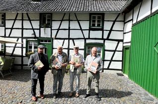 Karl-Heinz Huppertz, Ernst Palm und Günter Krings (v.r.) präsentieren das neue Buch des Eifelvereins Konzen über alte Häuser und ihre Bewohner wie das von Dieter Call (l.), das 1877 auf Aderich errichtet wurde und bis heute erhalten ist.