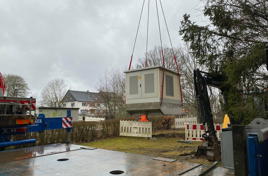 Die neue digitale Ortsnetzstation "Dietrichshöhe" in Büchenbeuren schwebt auf ihren Platz.