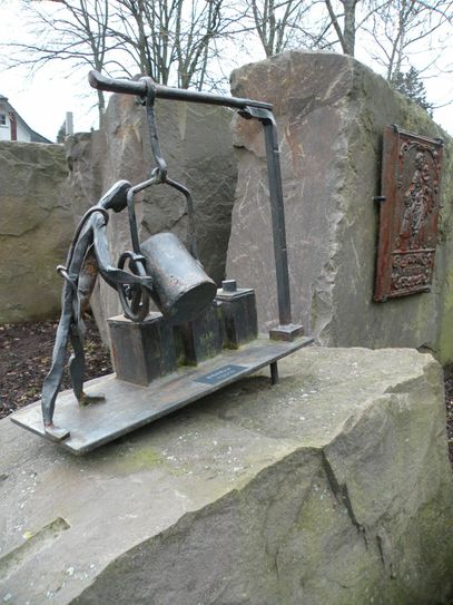 Am Eisen-Wanderweg in Gemünd-Mauel: Der knapp drei Kilometer lange Eisen-Wanderweg in Gemünd mit seinen acht anschaulich gestalteten Stationen verdeutlicht, dass hier einst ein Zentrum der Eisenproduktion war – lange bevor das Ruhrgebiet zur Stahlschmiede Deutschlands wurde. Im Gemünder Ortsteil Mauel ist ein Eisenhüttenstandort seit dem 15. Jahrhundert verzeichnet. Erhalten haben sich davon noch der Obergraben und ein Wehr. An drei Stationen in Mauel wird der Abbau von Eisenerz, dessen Verarbeitung und die Gewinnung von Holzkohle zum Schmelzen und Schmieden des Eisens erläutert. Neben archäologischen Führungen zu den Relikten der Eisenindustrie, bietet Gabriele Harzheim familiengerechte Führungen an. Groß und Klein können sich im Schmieden üben. Für die anschließende Stärkung der Gäste sorgt der Frauenclub Mauel mit einer rustikalen Brotzeit und Bratwurst im Brötchen von Anno Pief, später Kaffee und Kuchen.