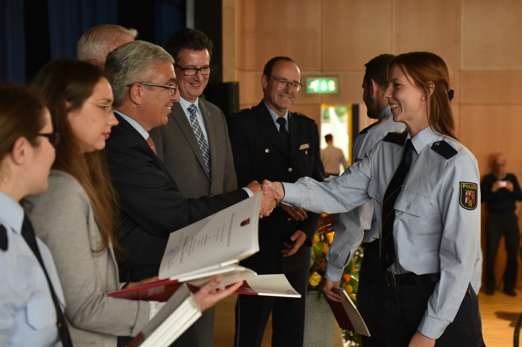 Endlich geschafft. Gerne nehmen die Absolventinnen und Absolventen der Hochschule der Polizei ihre Urkunden von Staatsminister Lewentz entgegen. Foto: FF