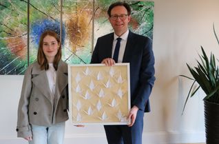 Lara Hahn überreicht Landrat Andreas Hackethal einen liebevoll gestalteten Bilderrahmen mit einigen der filigranen Papierkunstwerken, der künftig das Foyer des Kreishauses in Wittlich schmücken wird.