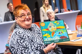 Künstlerin Petra Schneider präsentiert das Titelbild des Kalenders für 2027. Ihr farbenfroher Fisch schmückt die Jubiläumsausgabe.