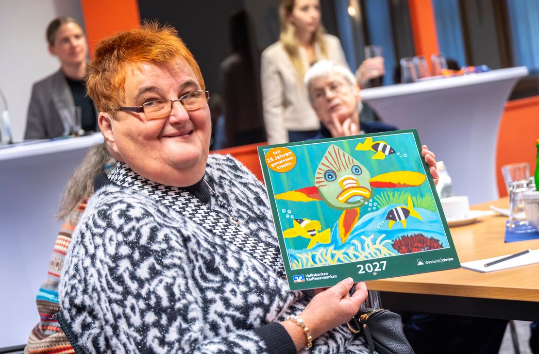 Künstlerin Petra Schneider präsentiert das Titelbild des Kalenders für 2027. Ihr farbenfroher Fisch schmückt die Jubiläumsausgabe.