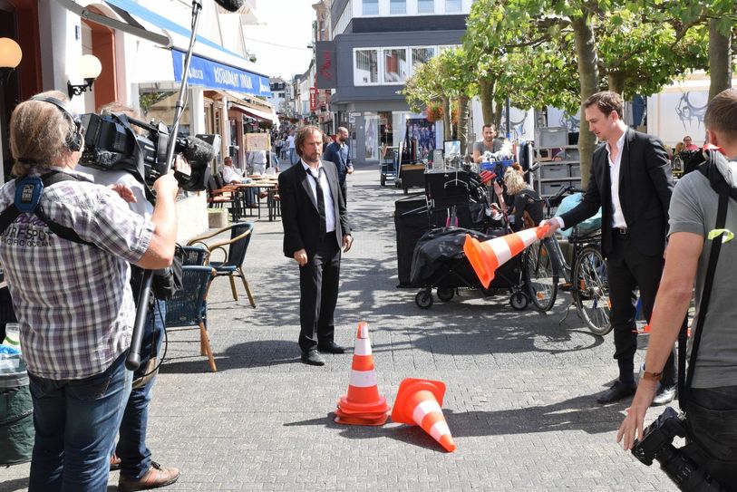 Die Hauptdarsteller vertreiben sich die Pausen zwischen den Drehs mit einem Hütchenspiel. Foto: Tim Nolden