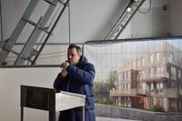Sascha Reichelt begrüßte die Gäste, im Hintergrund sieht man den Entwurf eines Hauses, das auf dem Areal gebaut werden soll.
