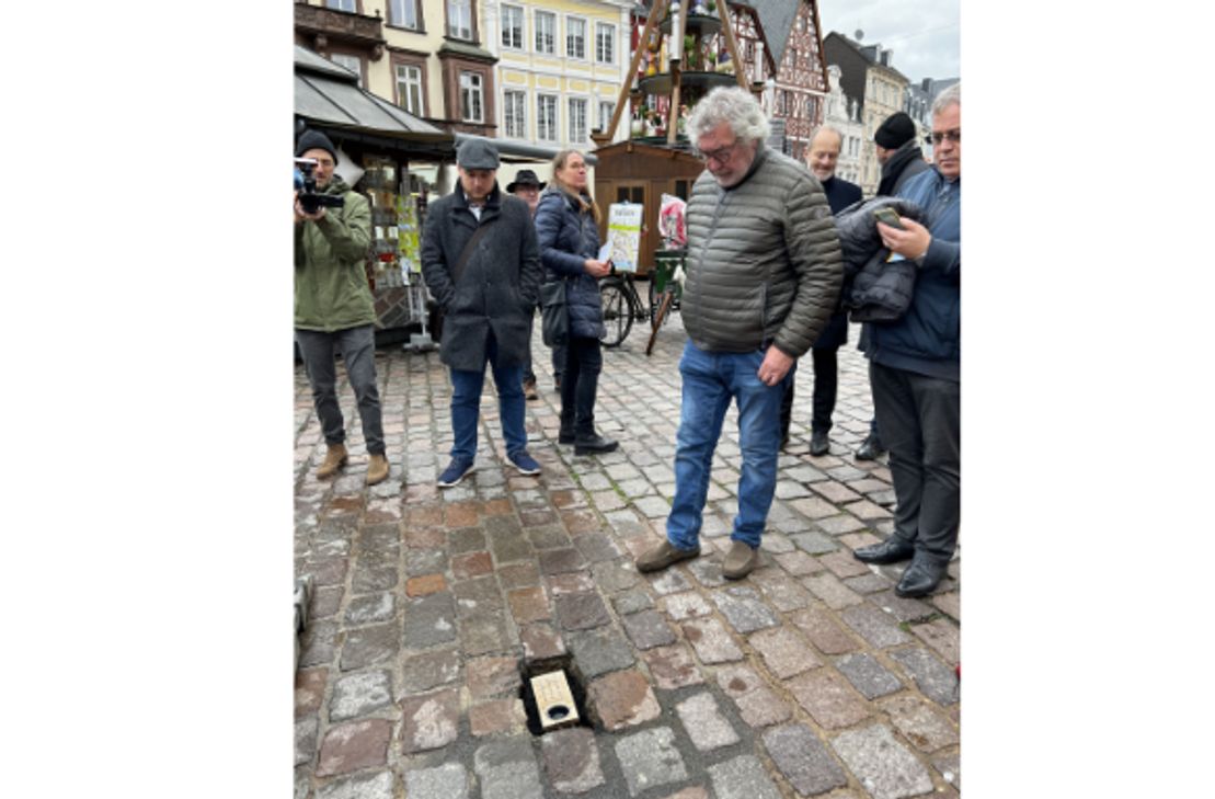 Guy Charlier (rechts) hat die Bronzeplaketten gestaltet. Auf dem Hauptmarkt erinnert nun eine davon an den hier bei der Amokfahrt ermordeten Dr. Georgios Kobiliris. Einge Meter weiter starb bei der noch immer unfassbaren Tat vor drei Jahren auch dessen erst wenige Wochen alte Tochter Virginia