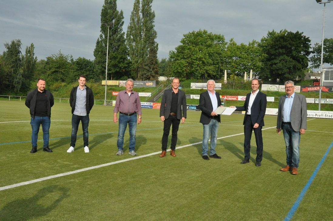 Staatsminister Clemens Hoch (2. v. r.)  konnte eine Landeszuwendung in Höhe von 99.900 Euro an Bernd Krayer (3. v. r.), Vorsitzender SV Eintracht Mendig, für die Sanierung des Kunstrasenplatzes an der Brauerstraße übergeben.