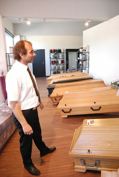 Bestatter Jörg Grandjean zeigt Särge verschiedener Holzarten. Foto: Huss