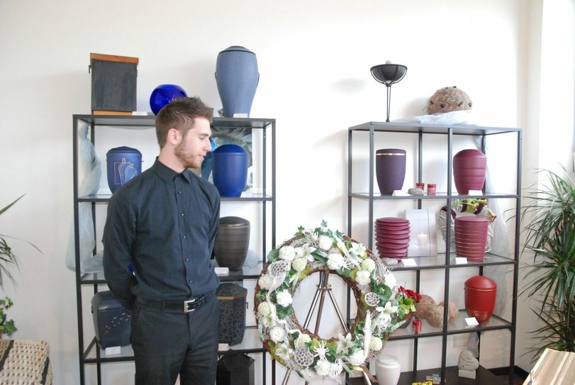 Der Auszubildende Philipp Müller vor Urnen-Regalen. Foto: Huss