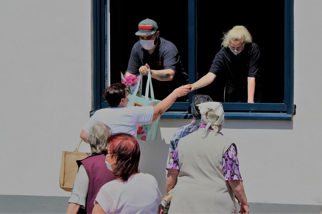 Am Fenster der Tafel-Gebäudes holen sich die Tafel-Kunden ihre gefüllten Einkaufstaschen wieder ab. Insgesamt versorgt die Euskirchener Tafel 650 Menschen (230 Gruppen und Familien), die von ihrer Hilfe abhängig sind – Tendenz steigend. Foto: Walter Feckinghaus